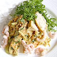 Krydret kyllingsalat med reker og grønnsaker servert i naanbrød